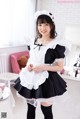 A woman dressed in a maid outfit posing for a picture.