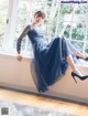 A woman in a black dress sitting on a window sill.