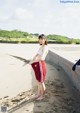 A woman in a white top and red shorts standing on a beach.