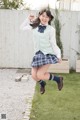 A young woman in a school uniform jumping in the air.