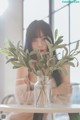 A woman sitting at a table with a vase of flowers in it.