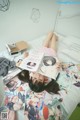 A woman laying on a bed covered in magazines.