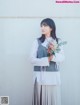 A woman standing in front of a white wall holding a bouquet of flowers.